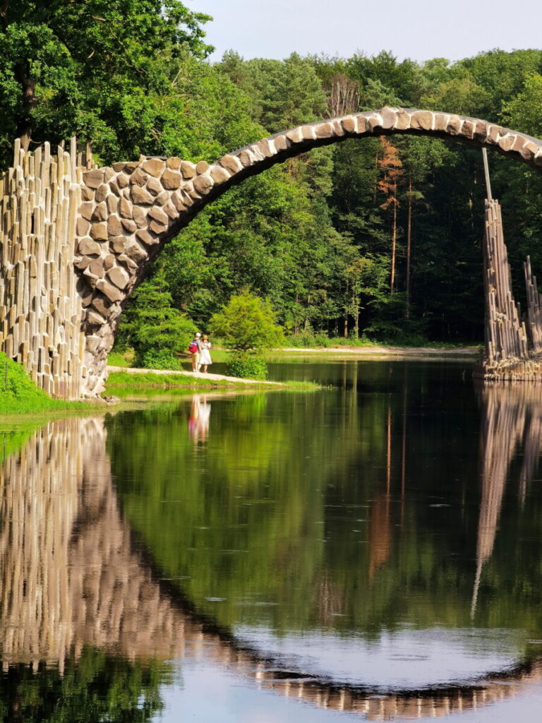 Der Bogen der Rakotzbrücke ist riesig - schau mal wie klein die Menschen im Vergleich sind